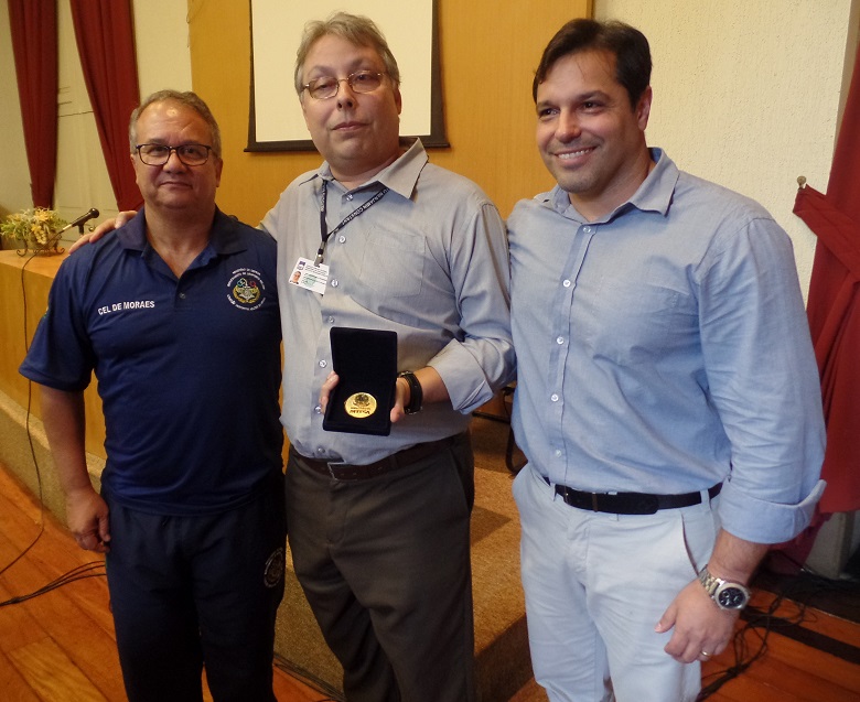 O diretor-geral João Ricardo (centro) recebe medalha do coronel De Moraes (esquerda), na presença de Fábio Brandolin (direita).